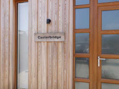 A wooden door with glass panels and a wooden sign reading Casterbridge at Upwey near Weymouth