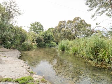 A shallow river with clear water surrounded by greenery and trees at Casterbridge in Upwey near Weymouth
