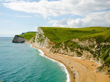 A beach with white cliffs and green grass above at Casterbridge in Upwey near Weymouth