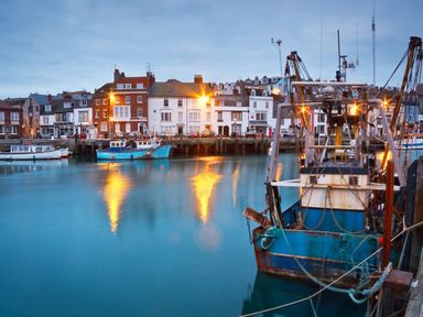 A harbor with fishing boats and buildings along the waterfront at Casterbridge in Upwey near Weymouth