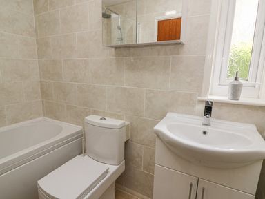 A bathroom with a bathtub toilet sink and a window with a soap dispenser at Trederwen in Rhayader