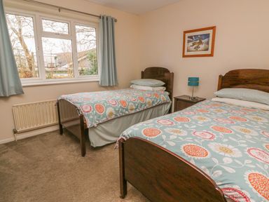 A bedroom with two single beds a window bedside table and a framed picture at Trederwen in Rhayader