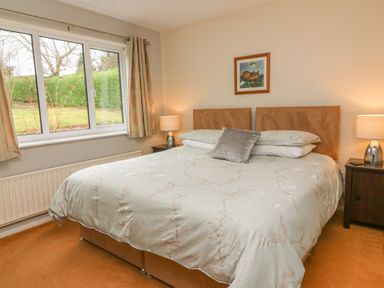 A bedroom with a double bed bedside tables lamps a window and a framed picture on the wall at Trederwen in Rhayader