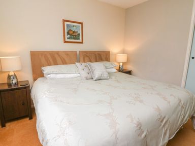 A bedroom with a large bed two bedside tables with lamps and a framed picture above the bed at Trederwen in Rhayader