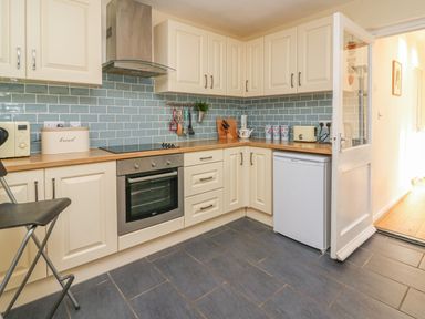 A kitchen with white cabinets a stove oven and a small refrigerator at Trederwen in Rhayader