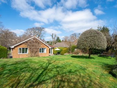 A brick house with two windows and a grassy yard with a tree and bench at Trederwen in Rhayader