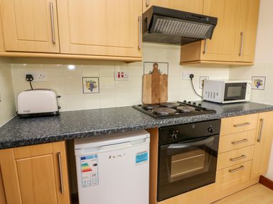 A kitchen countertop with a toaster microwave cutting board stove and oven at Red Kite Cottage in Howey near Llandrindod Wells