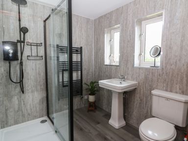A bathroom featuring a shower, toilet, and sink at Red Kite Cottage Howey near Llandrindod Wells