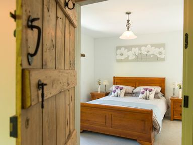 A bedroom with a wooden bed and two bedside tables with lamps at Mill Cottage Hanley William near Tenbury Wells