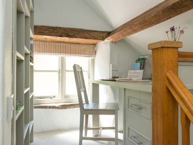 A small study area with a chair a window with a striped blind and a wooden beam at Mill Cottage in Hanley William near Tenbury Wells