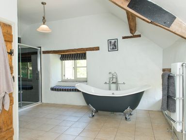 A bathroom with a clawfoot bathtub window seat and tiled floor at Mill Cottage in Hanley William near Tenbury Wells