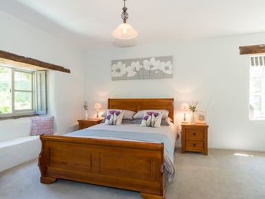 A bedroom with a wooden bed and two bedside tables with lamps at Mill Cottage in Hanley William near Tenbury Wells