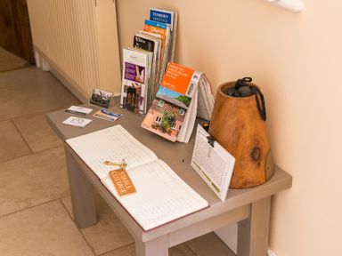 A small table with guest books brochures and a wooden container at Stable Cottage Hanley William near Tenbury Wells