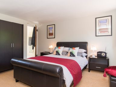 A bedroom with a double bed a red throw pillows bedside tables lamps and a wardrobe at Stable Cottage Hanley William near Tenbury Wells