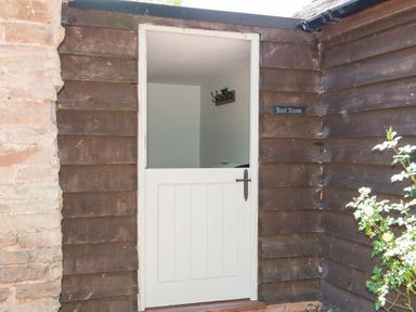A half door open showing an entryway with coat hooks on the wall at Stable Cottage in Hanley William near Tenbury Wells