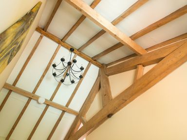 A ceiling with wooden beams and a black chandelier at Stable Cottage Hanley William near Tenbury Wells