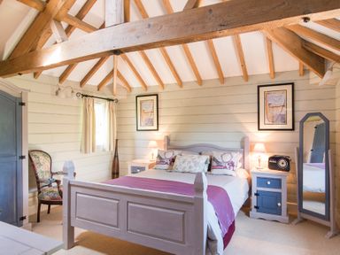 A bedroom with a bed bedside tables a standing mirror a wardrobe and a chair at Stable Cottage in Hanley William near Tenbury Wells