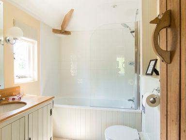A bathroom with a bathtub shower combination sink with wooden countertop and toilet at Stable Cottage in Hanley William near Tenbury Wells