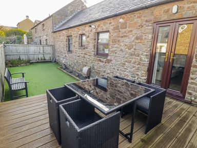 A garden area with a dining table and chairs at Corner Cottage Broad Haven