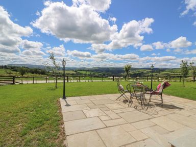 A patio with metal chairs and lamps overlooking a field with sheep at Valley View in Rhayader