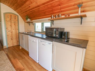 A kitchen with wooden floor cabinets countertop microwave toaster and a small fridge at Valley View in Rhayader