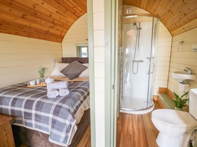 A bedroom with a double bed and a bathroom with a shower toilet and sink at Valley View in Rhayader