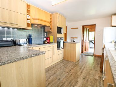 A kitchen with wood cabinets and appliances at Dragonfly Lodge in Whinburgh near Dereham