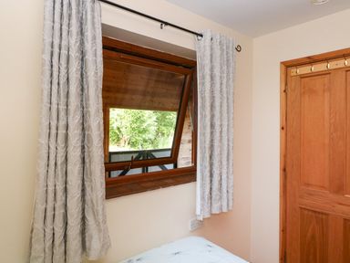 A bedroom with a window and curtains at Dragonfly Lodge Whinburgh near Dereham