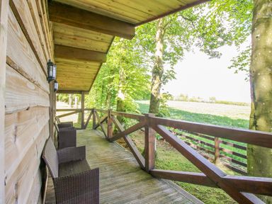 A wooden deck with chairs and a lantern at Valley View Lodge in Welshpool