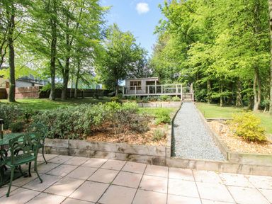 A garden with a gravel path leading to a wooden structure at Valley View Lodge in Welshpool