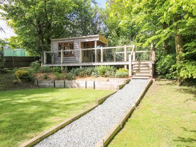 A garden with a wooden cabin and gravel path at Valley View Lodge Welshpool