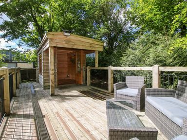 A wooden cabin with outdoor furniture in the garden at Valley View Lodge in Welshpool