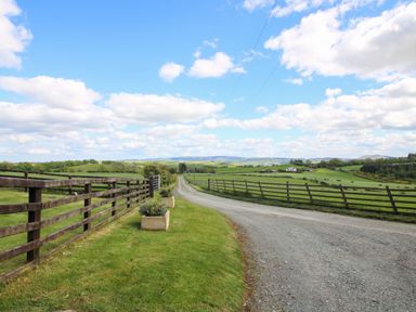 A landscape view with a driveway and fence at Valley View Lodge in Welshpool