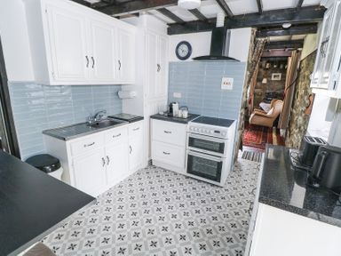 A kitchen with white cabinets blue tiled backsplash and patterned floor at Dun na Ron in Oughterard County Galway