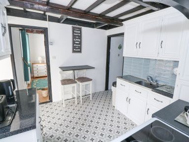 A kitchen with white cabinets a black countertop patterned floor tiles and a small dining table with two chairs at Dun na Ron in Oughterard County Galway