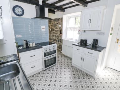 A kitchen with a stove sink coffee machine toaster kettle and cabinets at Dun na Ron in Oughterard County Galway