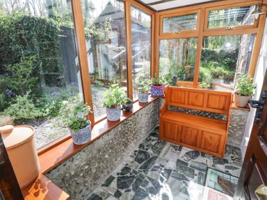 A sunroom with stone floor wooden bench and potted plants on windowsills at Dun na Ron in Oughterard County Galway