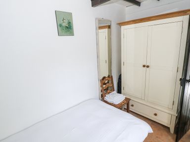 A bedroom with a bed a wooden chair with towels a tall mirror and a white wardrobe at Dun na Ron in Oughterard County Galway