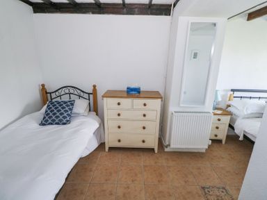 A bedroom with two single beds separated by a chest of drawers and a wall with a mirror and radiator at Dun na Ron in Oughterard County Galway