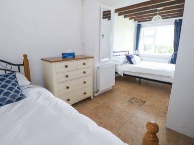 A bedroom with two beds a chest of drawers and a window with curtains at Dun na Ron in Oughterard County Galway