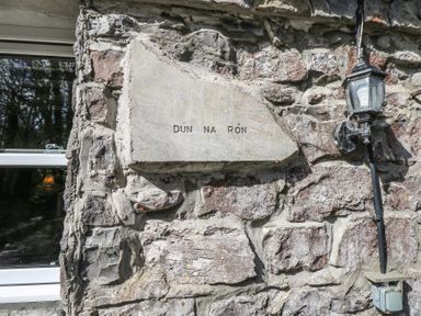 A stone wall with a plaque reading Dun na Ron a window and a wall-mounted lantern at Dun na Ron in Oughterard County Galway
