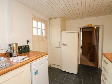 A kitchen with a refrigerator dishwasher countertop kettle and cabinets at Nantmel in Beddgelert