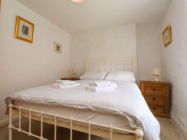 A bedroom with a double bed white bedding wooden bedside tables lamps and framed pictures on the walls at Nantmel in Beddgelert