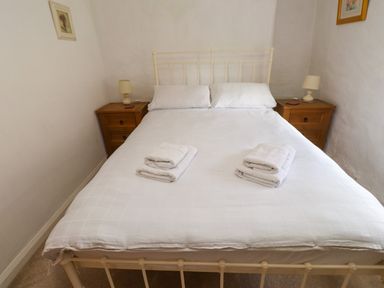 A bedroom with a double bed two bedside tables with lamps and folded towels on the bed at Nantmel in Beddgelert