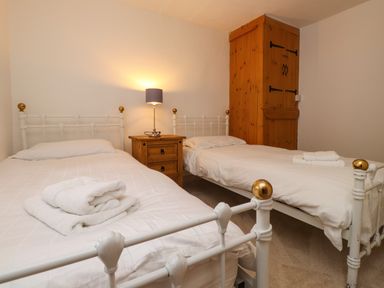 A bedroom with two single beds a wooden nightstand with a lamp and a wooden wardrobe at Nantmel in Beddgelert