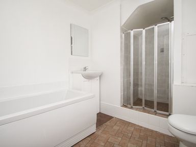 A bathroom with a bathtub sink mirror shower enclosure and toilet at Tregiffian Vean in Sennen Cove