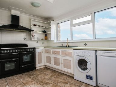 A kitchen with stove, washing machine and dishwasher at Tregiffian Vean in Sennen Cove