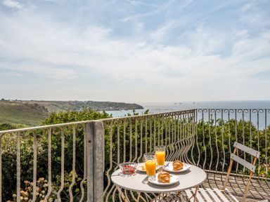 A table with croissants and orange juice on a balcony overlooking the sea at The Lookout in Sennen