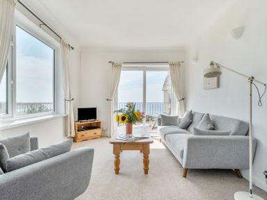A living room with a sofa, armchair, and coffee table at The Lookout in Sennen