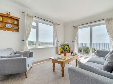 A living room with a sofa, coffee table and flowers at The Lookout in Sennen